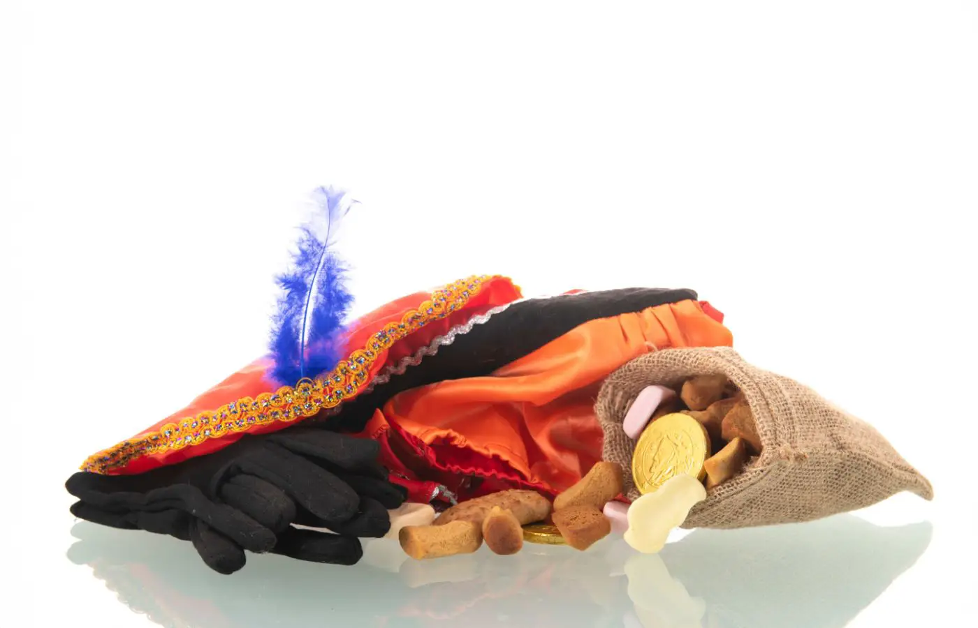 Traditionele accessoires van Zwarte Piet, waaronder een kleurrijke hoed met blauwe veer, zwarte handschoenen, een juten zak en Sinterklaassnoep zoals pepernoten en chocolademunten.